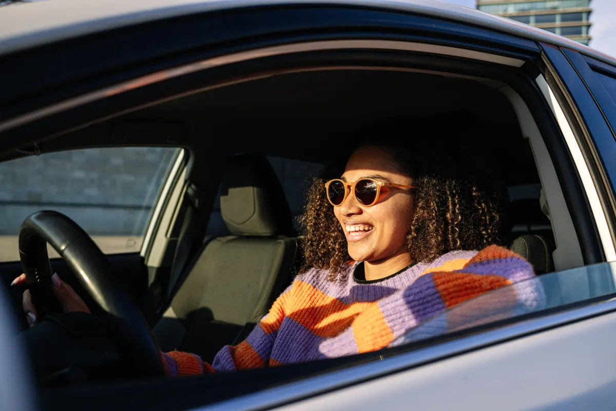 Motorista sorrindo ao volante, protegida pelo Seguro Auto Spadina em Campinas